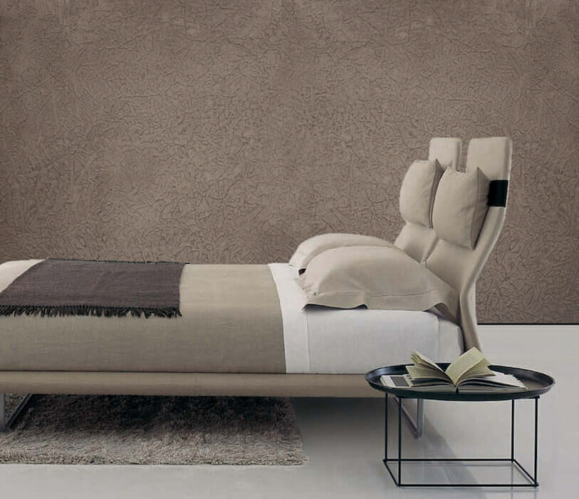 Braune Kalkwand mit leichter Struktur hinter einem Bett